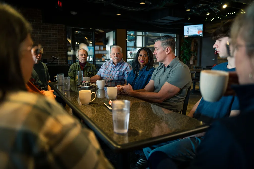 Democratic congressional candidate Matt Maasdam speaks with a group seated around a table.