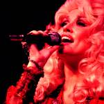 A closeup on Dolly Parton singing with a mic in her hand.