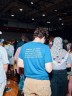 A person is shown from the back with a shirt that says "Freeze the Rent. Fare Free Buses. $30 Minimum Wage. No Cost Childcare. Affordable Housing"