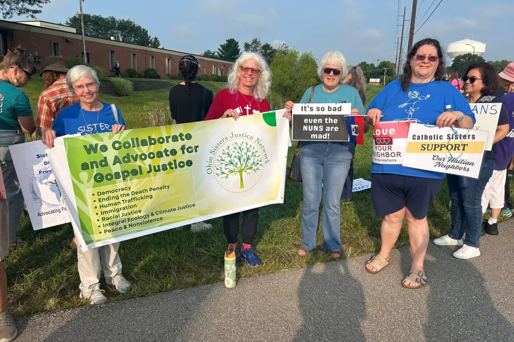 A group of Catholic sisters stands with signs outside an ICE office.