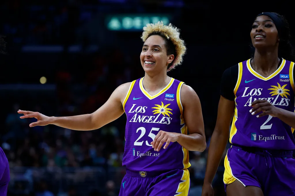 Two Los Angeles basketball players in purple uniforms walk on the court.