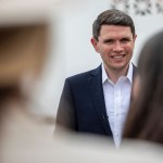 James Talarico smiles as he talks to local officials after a campaign stop.