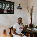 Crystal Mason sits hat a table in a room surrounded by photos of famous Black activists.