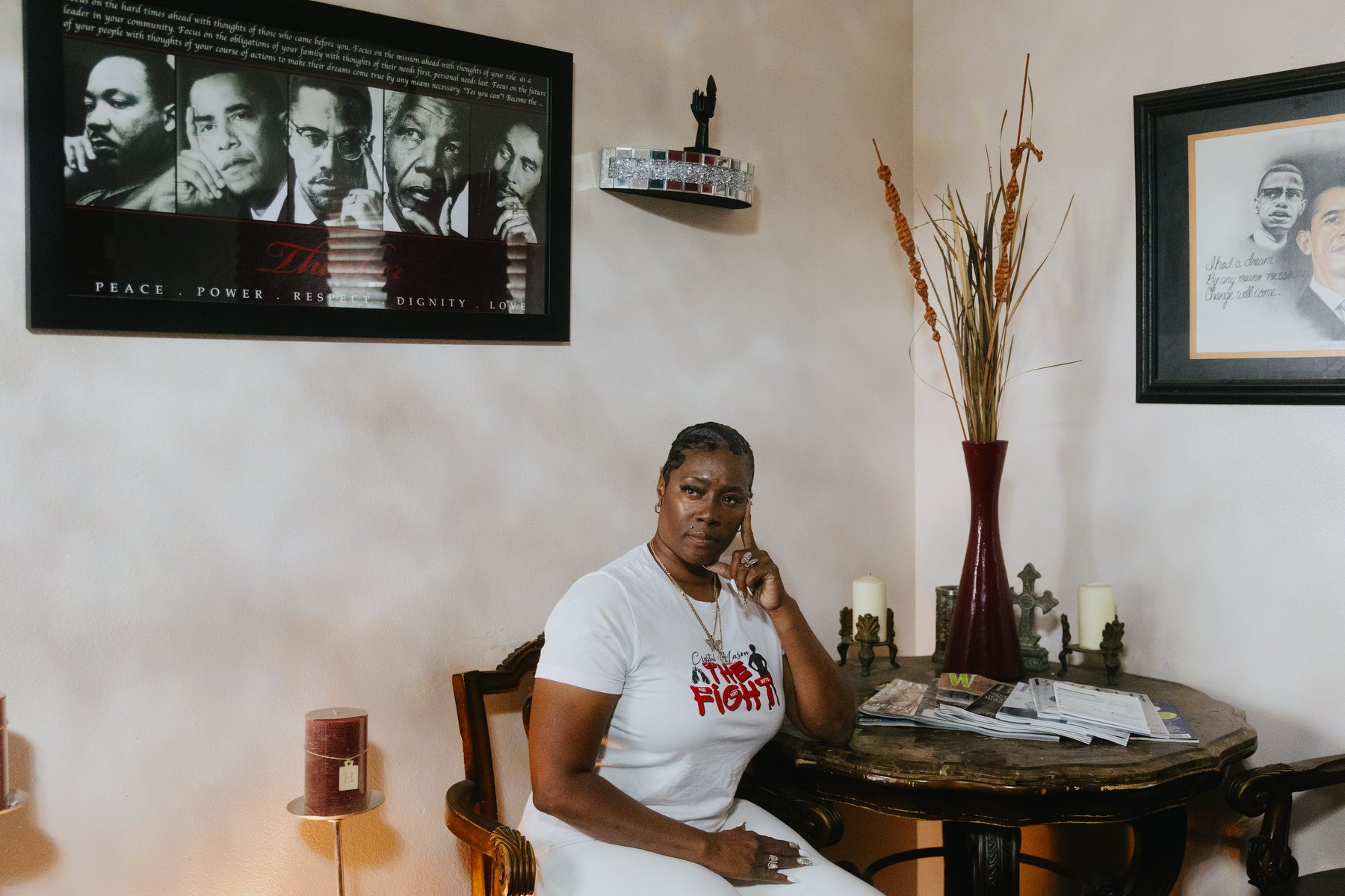 Crystal Mason sits hat a table in a room surrounded by photos of famous Black activists.