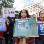 A group of protestors hold signs saying Hands off the EEOC.