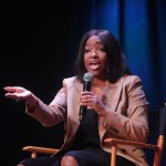 Rep. Jasmine Crockett speaks on stage while holding a microphone during an event in Phoenix, Arizona