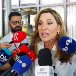 Rep. Maria Elvira Salazar speaks to reporters as a crowd of microphones surrounds her during a press scrum.