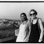 Bell Hooks stands beside Steinem against a coastal backdrop, smiling at the camera.
