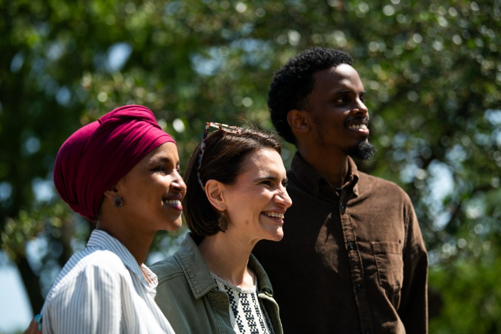 Flanagan and Fateh stand together with Rep. Ilhan Omar, all smiling at someone outside the frame