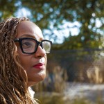Darnese Foster with braided hair and black-framed glasses looking into the distance outdoors.