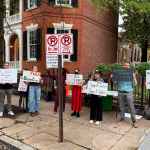 Several people hold protest signs on a street.