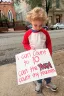 A child holds a protest sign on a street.