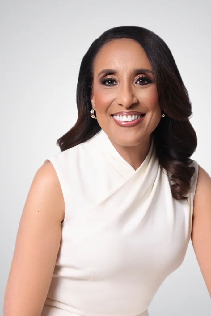 A portrait of Reynolds wearing white against a white backdrop and smiling into the camera. Black women in politics