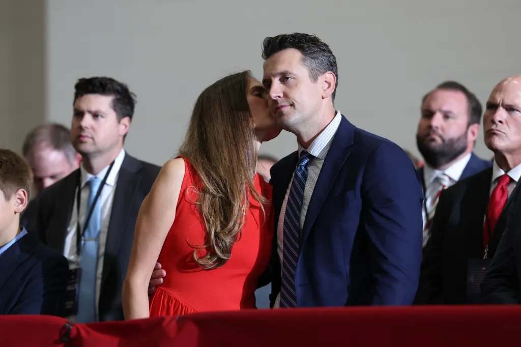 Lahn's wife kisses him on the cheek surrounded by others.