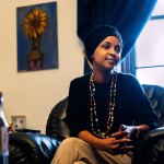 A portrait of Omar sitting on a chair in an office.