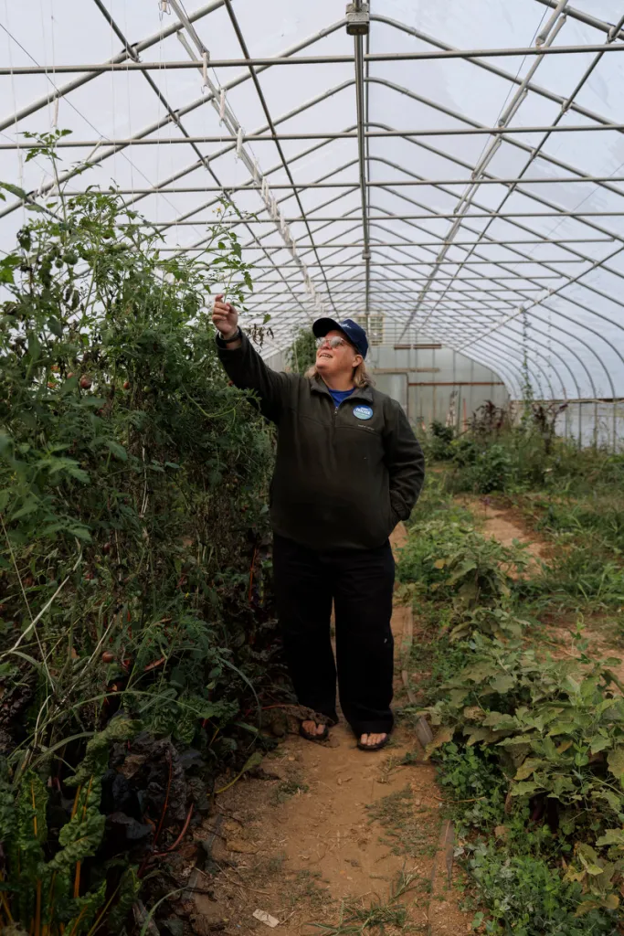 Portrait of Thacker reaching up to touch a leaf in a greenhouse
